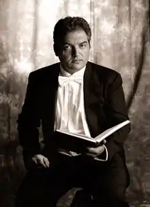 Photo of man in white tie holding open book