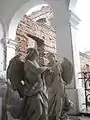 Statues of angels in a heraldic setting, with ruins in the background, before renovation