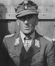 A man wearing a military uniform with an Iron Cross displayed at the front of his uniform collar.