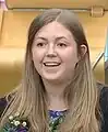 Official Portrait of Christine Grahame MSP. She is smiling, with short blonde hair and a colourful top. There is a grey-ish background.