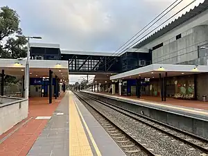 View from platform of two side platforms with station shelters and an overpass