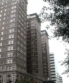 High rise brick, flat-roofed hotel with three wings of equal size resting on the base provided by the first two floors.