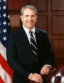 man in business suit, American flag in background