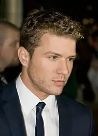 A blonde man in a suit looks away from the camera