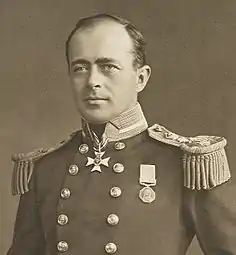  Man with receding hairline, looking left, wearing naval uniform with medals, polished buttons and heavy shoulder decorations