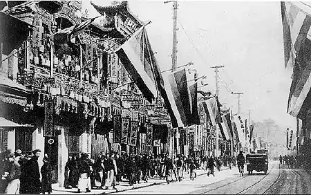 Black and white street scene with multiple buildings hanging Five Races Under One Union flags used by the rebels of the 1911 Revolution