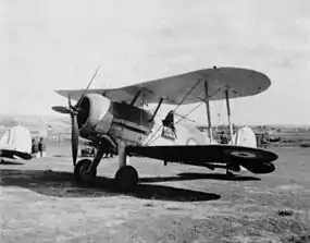 Single-engined military biplane parked on airfield